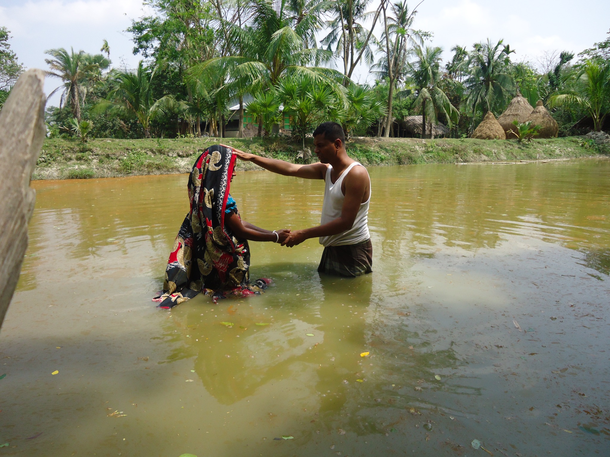 A baptism taking place in a village pond