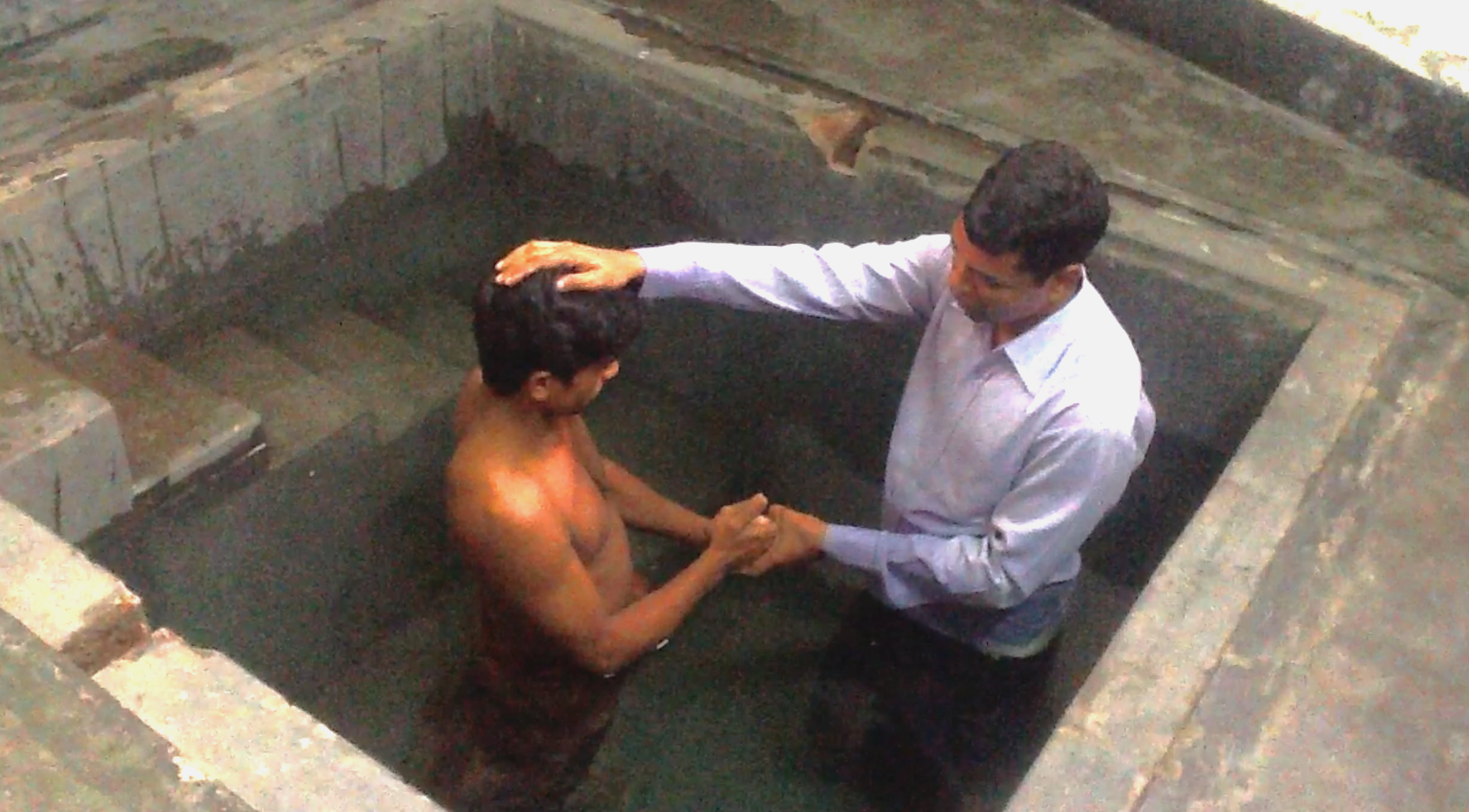 A baptism taking place in a baptismal pool
