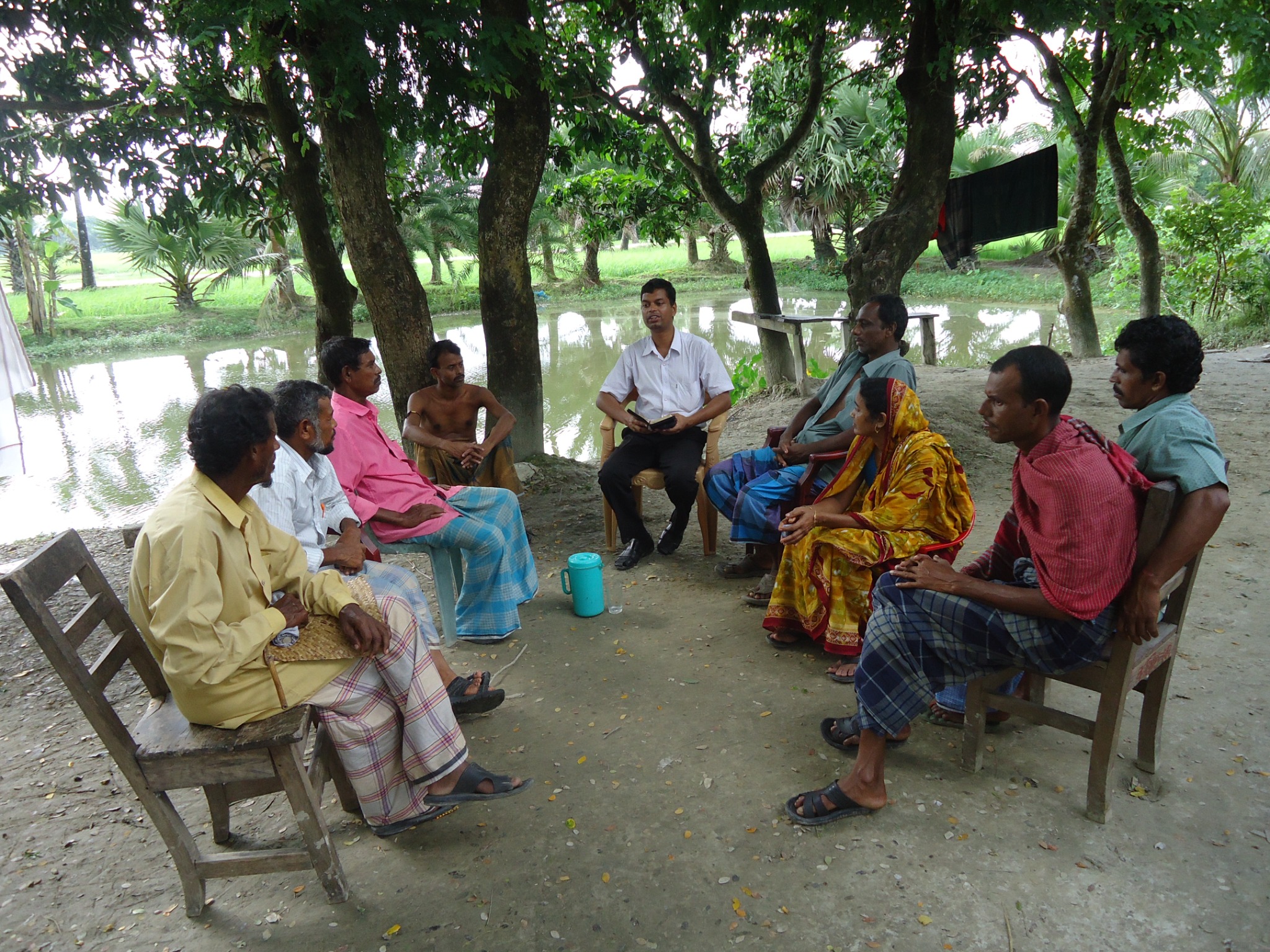 Community members meeting outdoors beside a pond